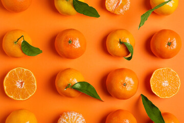 Delicious tangerines and green leaves on orange background, flat lay