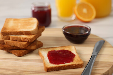 Breakfast time. Crunchy toasts and jam on wooden board, closeup