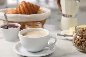 Breakfast time. Fresh coffee, granola, croissants, jam and honey on white table, closeup