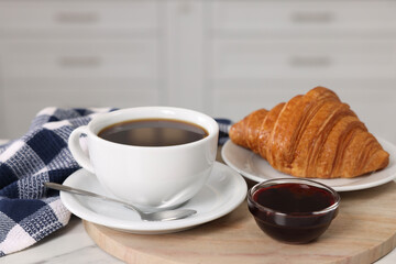 Breakfast time. Fresh croissant, coffee and jam on white table, closeup