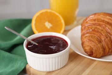 Breakfast time. Fresh croissant and jam on wooden board, closeup