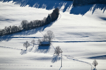 Winterlandschaft, kleine Scheune mit einzelnen Bäumen an einem Hang der mit Schnee bedeckt ist....