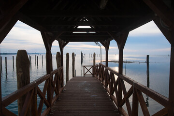Le luci del tramonto viste dall'interno di un molo di legno dell'isola di Pellestrina nella laguna di Venezia