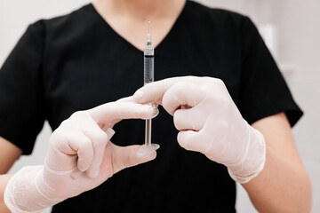Hand holding a syringe, the syringe is filled with clear liquid. Injection procedure. Lip...