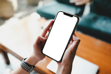 Close up of woman using cell white blank screen phone and sending massages in the coffee shop.