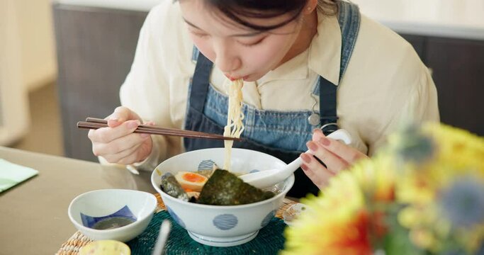 Japanese woman in restaurant, eating noodles and food for lunch or dinner. Ramen, bowl or hands of a young hungry person, customer or girl with chopsticks to enjoy healthy meal or traditional cuisine