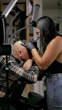 micropigmenter tattooing hair on the head of a man who has baldness