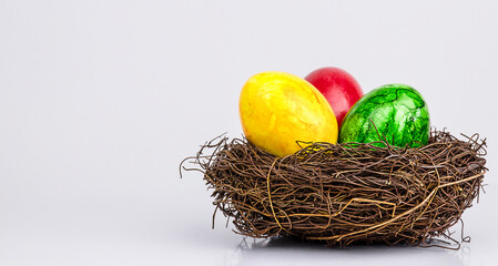 Three colorful Easter eggs in a nest on a gray background. Copy Space. Easter concept