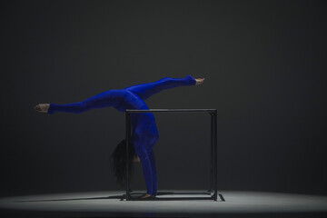 Portrait of female acrobat isolated on black background. Woman gymnastic dancer in blue sparkling...