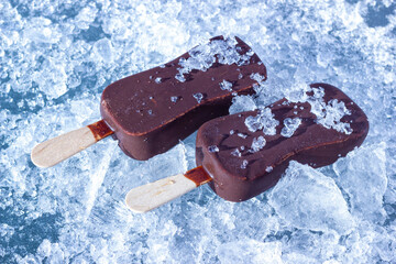 The chocolate coated ice cream bars on wooden stick on the chopped ice crystals.  - 723966370