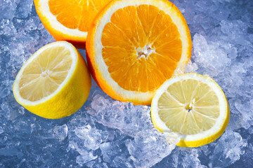 The sliced orange and lemon on chopped ice background. Fresh and natural juicy fruits on the frozen icy crystals. Refreshment food with vitamins.