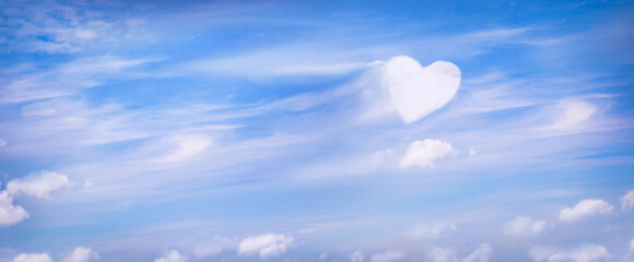 Fluffy clouds forming a heart shape on blue sky background, soft focus. Heavenly clouds. Holidays...