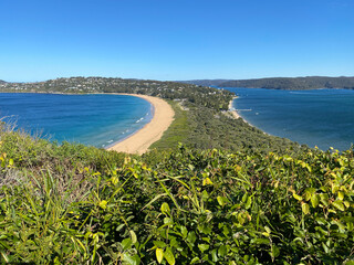 Narrow peninsular surrounded by water on two sides. Panorama of the ocean. View of the mountain and the island's coastline. Palm beach, Australia. Beach that divides the ocean.