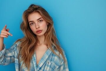 Fototapeta premium Portrait of a beautiful young woman with long blond hair and freckles in a blue shirt on a blue background