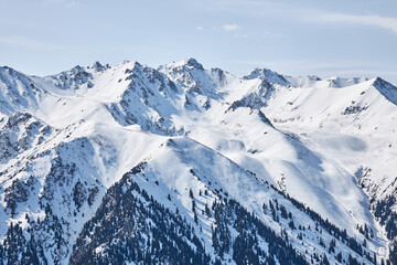 Panoramic view from top of slope on snow capped high mountains. Karakol ski resort in Kyrgyzstan....