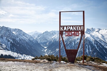 Karakol ski resort. Sign on top of the mountain height 3040 meters above sea level. Panoramic view on winter mountains in Kyrgyzstan. Snowy peaks, natural landscape at sunny day. - obrazy, fototapety, plakaty