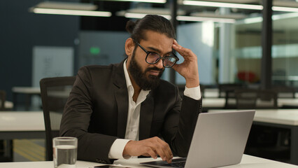 Bored Arabian business man at office table tired Indian clerk businessman worker sad dissatisfied...