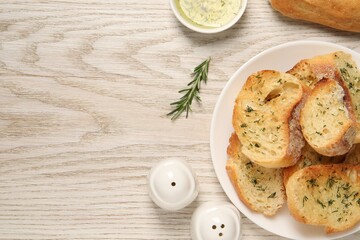 Tasty baguette with garlic, dill, rosemary and oil on white wooden table, flat lay. Space for text