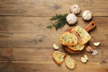 Tasty baguette with garlic and dill on wooden table, flat lay. Space for text