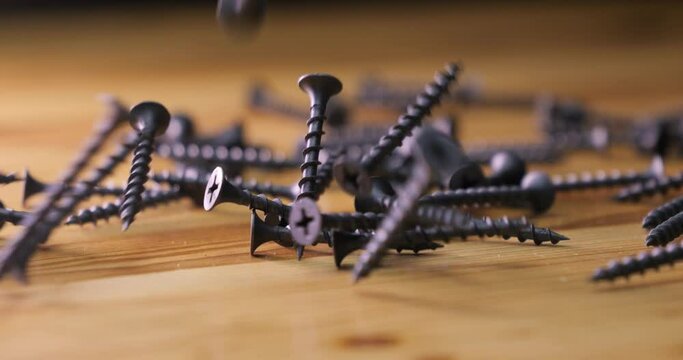 Metal self-tapping screws spill out onto a wooden tabletop. Make wooden products. Start repair or construction. Building materials and bolts and nails.