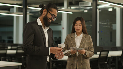 Arabian happy businessman with many money man count banknotes and sad Asian businesswoman woman...