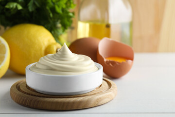 Fresh mayonnaise sauce in bowl on white wooden table, closeup. Space for text