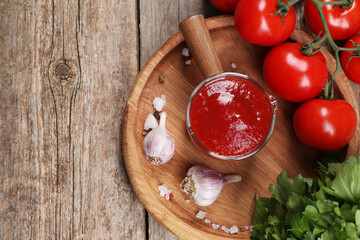 Delicious ketchup, spices and products on wooden table, top view with space for text. Tomato sauce