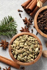 Different aromatic spices and fir branches on light textured table, flat lay