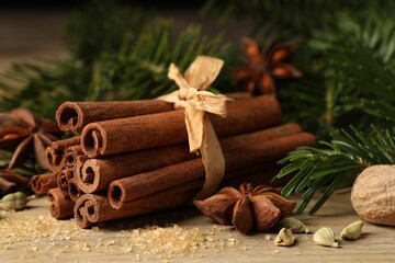 Different aromatic spices and fir branches on wooden table, closeup