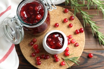 Cranberry sauce, fresh berries and rosemary on wooden table, flat lay