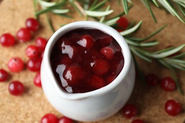 Cranberry sauce in pitcher, fresh berries and rosemary on board, above view