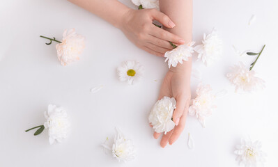 Closeup beautiful sophisticated female hands with pink flowers on white background. Concept hand care, anti-wrinkles, anti-aging cream spa