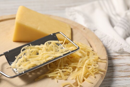 Grated, whole piece of cheese and grater on wooden rustic table, closeup