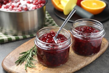Fresh cranberry sauce in glass jars served on gray table, closeup