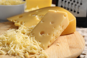 Grated and cut cheese on wooden board, closeup