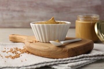 Tasty mustard sauce and dry seeds on light table