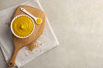 Tasty mustard sauce and dry seeds on light textured table, flat lay. Space for text
