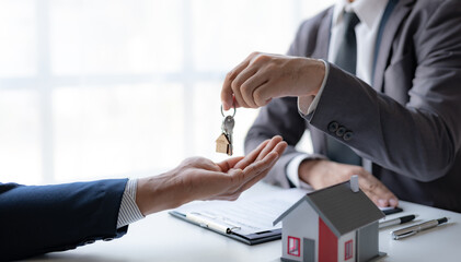 A professional real estate agent is giving house keys to a client during a property sale...