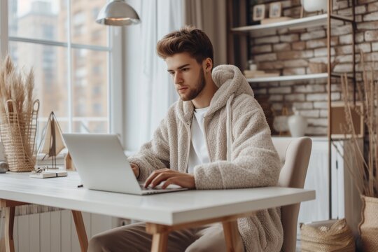 Focused young man working on laptop in home office