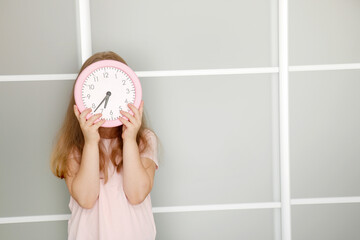 girl holding a watch in her hands covering her face with it