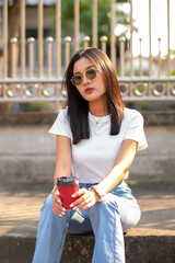 Young woman with good looks and cool vintage clothes Holding a red coffee mug, she poses for the camera.