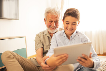 Grandson and grandfather using tablet PC at home