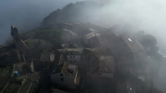 aerial view with the drone of the medieval village of Fiorenzuola di Focara immersed in the fog. We are in the San Bartolo park between Pesaro and Romagna