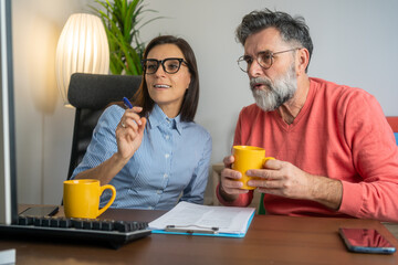 Portrait of success business people working together in home office. Couple teamwork startup concept. Two busy diverse professional coworkers discussing work using pc computer in office.