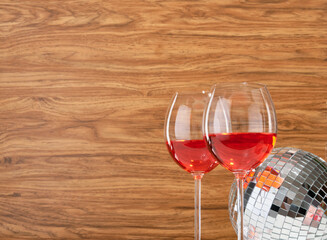 Champagne glasses and disco ball for night club dance party on a wooden background. Copy space for text.