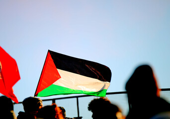 Palestinian flag waved during the peaceful demonstration with many people to stop the war