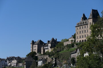 Fototapeta premium Uzerche, a picturesque French city, graces the hillside with its timeless charm during the summer. The city view reveals a tapestry of old buildings adorned with architectural elegance.