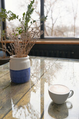 coffee with milk and ceramic pot with lavender at the kitchen table near the window, cozy coffee break