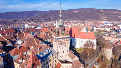 Obraz premium Birds eye view over Sighisoara city. Aerial photography of medieval city of Sighisoara from Romania, taken from a drone with the Clock Tower in the front. 