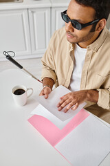 handsome indian man with blindness in casual attire with walking stick reading braille code